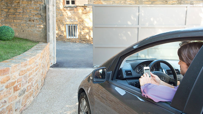 conducteur ouvre sa porte de garage motorisée depuis son smartphone grâce à la solution domotique Somfy