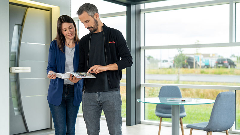 conseiller Komilfo montre le catalogue à une cliente dans un showroom